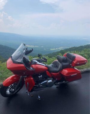 Custom shaved and covered Harley-Davidson touring seat featuring grey perforated material, orange stitching, matching rider backrest, and dual Tour-Pak cushions